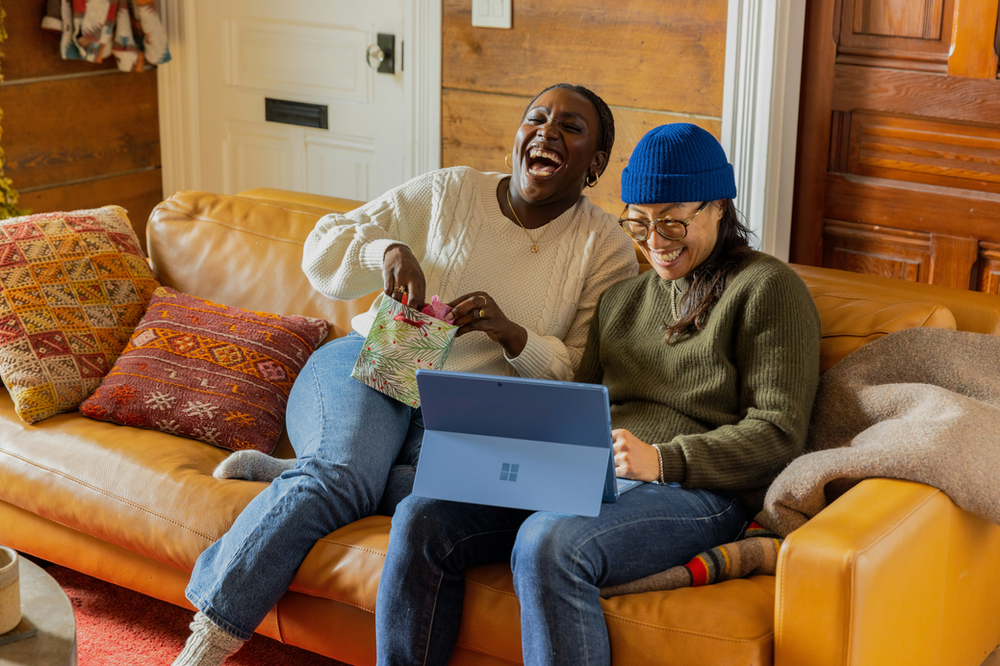 2 people laughing at jokes on a laptop